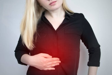 A woman holds on to his stomach. Pain in the abdominal cavity. The concept of diseases of the stomach and digestive system clipart