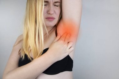 A woman suffers from pain in the armpit. Sweating, unpleasant odor, redness, tooth and inflammation in the armpit. Breast Cancer Prevention Concept clipart