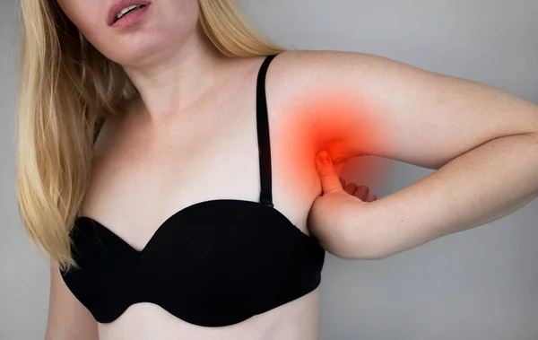 A woman suffers from pain in the armpit. Sweating, unpleasant odor, redness, tooth and inflammation in the armpit. Breast Cancer Prevention Concept