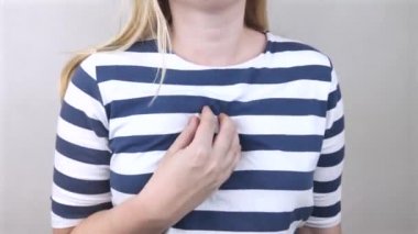 Kalp bölgesinde bir kadın onun göğsünü tutuyor. Kalp krizi ya da göğüs ağrısı. Kalp hastalığı konsepti ve acı belirtileri.