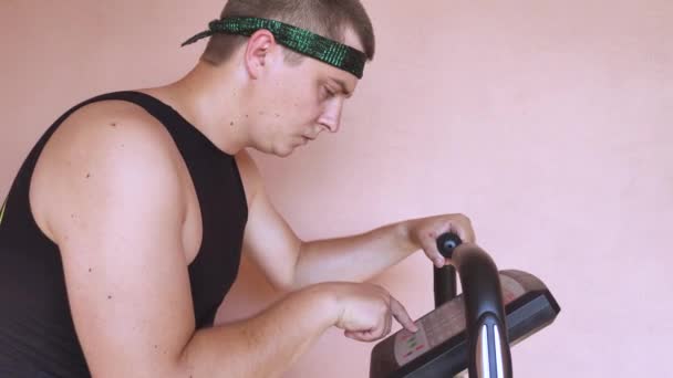 Fröhlicher Dicker Mann Lustigen Trainingsanzug Ist Mit Einem Stationären Fahrrad — Stockvideo