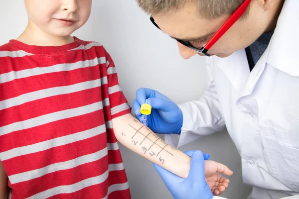 An allergist doctor makes a skin test for allergies. The boy is being examined in the laboratory, waiting for a reaction to allergens.
