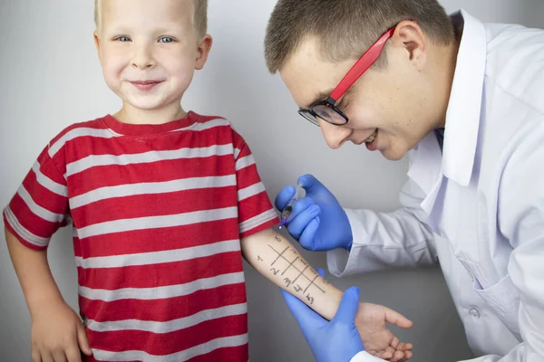 An allergist doctor makes a skin test for allergies. The boy is being examined in the laboratory, waiting for a reaction to allergens.