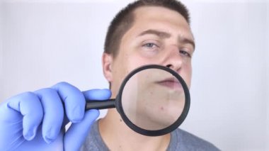 Sivilcelere yakın çekim. Bir kadın bir doktor tarafından muayene ediliyor. Dermatolog deriyi büyüteçle inceliyor, büyüteçle.