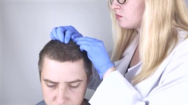Bir tricholog, saç dökülmesine başlayan bir adamın saçını inceliyor. Bir dermatologla görüşeceğim. Saç dökülmesi, alopezi, pruritus, yanmakta olan kafa ya da sebora.
