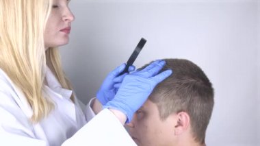 Bir tricholog, saç dökülmesine başlayan bir adamın saçını inceliyor. Bir dermatologla görüşeceğim. Saç dökülmesi, alopezi, pruritus, yanmakta olan kafa ya da sebora.