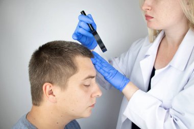 Bir tricholog, saç dökülmesine başlayan bir adamın saçını inceliyor. Bir dermatologla görüşeceğim. Saç dökülmesi, alopezi, pruritus, yanmakta olan kafa ya da sebora.