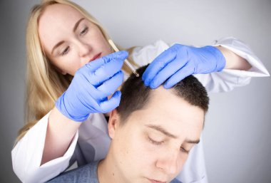 Bir trikoloğun doktoru serumu hastanın saçına damlatıyor. Alopecia tedavisi. Saç dökülmesi, alopezi, pruritus, yanmakta olan kafa ya da sebora.