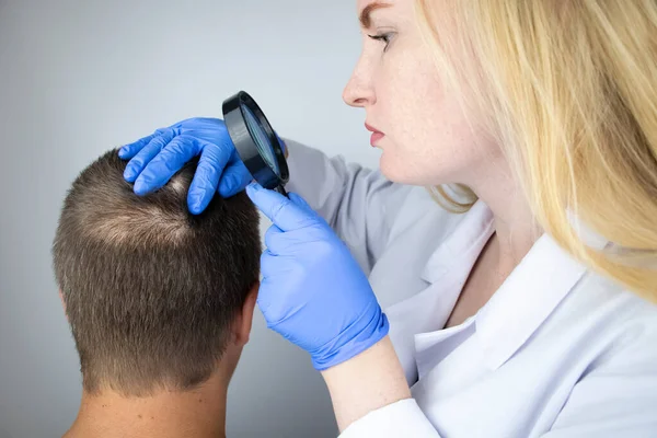 Bir tricholog, saç dökülmesine başlayan bir adamın saçını inceliyor. Bir dermatologla görüşeceğim. Saç dökülmesi, alopezi, pruritus, yanmakta olan kafa ya da sebora.