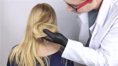 Bir doktor trichologist bir sarışının saçı üzerine bir çalışma yürütüyor. Alopecia tedavisi. Saç dökülmesi, alopecia, kaşıntı, kafa yanması, sebora ya da kırılgan son.