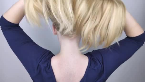 Blonde naturelle jette et peluche ses cheveux devant la caméra. Le concept de soins capillaires appropriés. Mouvement lent — Video