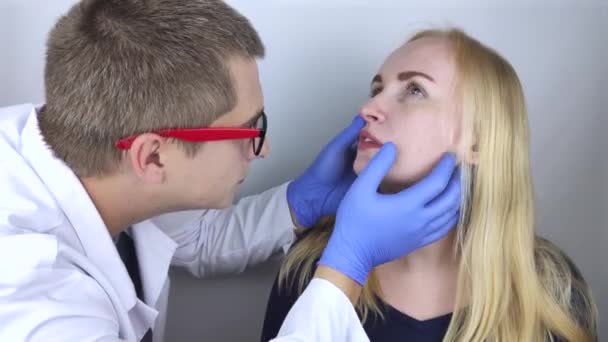 Az otolaringológus megvizsgálja a lány orrjáratát. Fájdalmas érzés az orrban, polipok, adenoidok és légszomj. Törések az orr porcszövetén. A nasopha lezárása — Stock videók