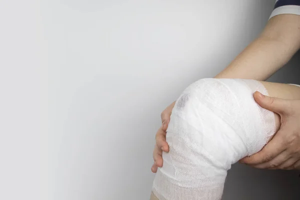 医者は負傷した少女の膝を包帯する 外傷に圧力包帯を適用することによって出血を停止します 負傷者の応急処置 十字形の包帯を適用する技術 — ストック写真