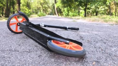 Scooter, bir sürücü düştükten sonra asfaltta yatar. Arka tekerlek dönüyor, düşüşün yakın zamanda olduğunu simgeliyor. Baştan savma sürüş ve acele konsepti