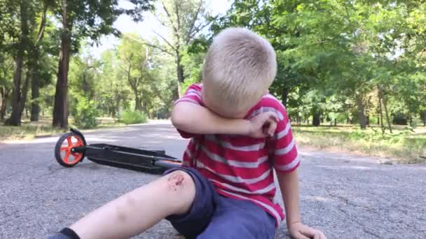 4歳の子供がスクーターを降りて膝を負傷した 子供は泣き 膝をこすり それに吹く ずさんな運転と親の不注意の概念 — ストック動画