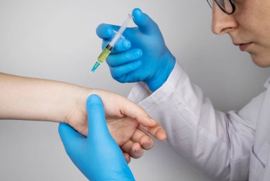 Bir ortopedi cerrahı bileğine iğne yapar. Hyaluronik asite dayanan hormonal ilaçlarla ya da ilaçlarla osteoartrit tedavisi. Eklem kıkırdağına zarar veren hastalıklara yardım