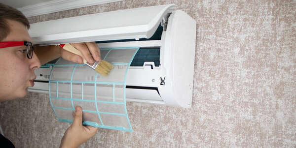 Cleaning the air conditioner from dust, mold and dirt. An air conditioner maintenance worker assesses the level of contamination, cleans the radiator and flushes out contamination from cavities.