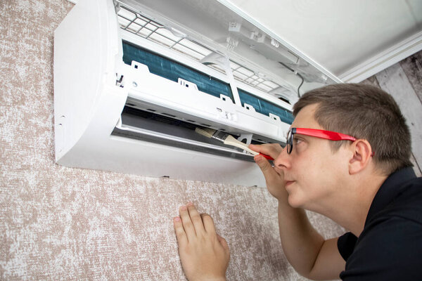 Cleaning the air conditioner from dust, mold and dirt. An air conditioner maintenance worker assesses the level of contamination, cleans the radiator and flushes out contamination from cavities.