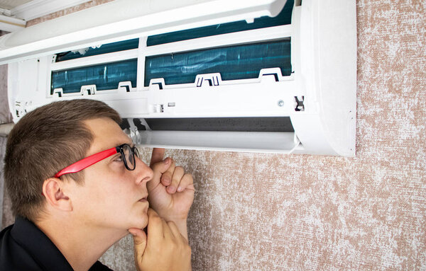 Cleaning the air conditioner from dust, mold and dirt. An air conditioner maintenance worker assesses the level of contamination, cleans the radiator and flushes out contamination from cavities.