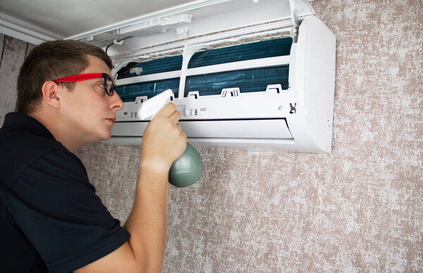 Cleaning the air conditioner from dust, mold and dirt. An air conditioner maintenance worker assesses the level of contamination, cleans the radiator and flushes out contamination from cavities.