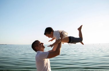 Şefkatli bir baba oğlunu havaya fırlatır ve onu yakalar. Çocuk güler ve babasına güvenir. Sevgi dolu ebeveynler ve çocuklara bakmak için bir yaşam tarzı. Baba sevgisi ve oyun kavramı..