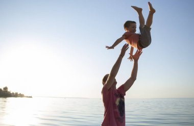 Şefkatli bir baba oğlunu havaya fırlatır ve onu yakalar. Çocuk güler ve babasına güvenir. Sevgi dolu ebeveynler ve çocuklara bakmak için bir yaşam tarzı. Baba sevgisi ve oyun kavramı..