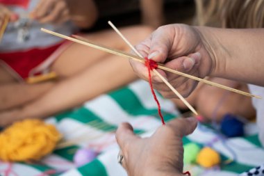El dokuması mandalalar. Sahilde bir öğretmen öğrencilerine dekoratif desenler örmeyi öğretiyor. Özel sembollerin yaratılması. Eğitim ve el işçiliği kavramı.