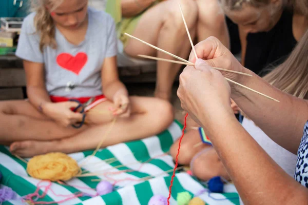 El dokuması mandalalar. Sahilde bir öğretmen öğrencilerine dekoratif desenler örmeyi öğretiyor. Özel sembollerin yaratılması. Eğitim ve el işçiliği kavramı.