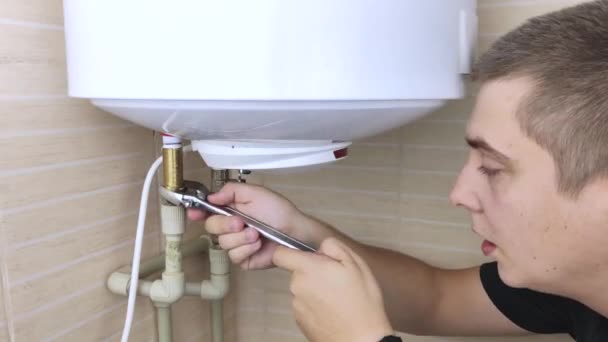 A locksmith fixes a boiler that is not working. The worker will check the electronics and unscrew the nut on the pipe with an adjustable wrench. Technical assistance concept — Stock Footage Locksmith Fixes Boiler Working Worker Check Electronics Unscrew Nut Pipe Stock Footage