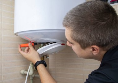 Kazan tamircisi su ısıtıcısındaki elektronik aletleri kontrol ediyor. Profesyonel yardım ve teknik destek kavramı