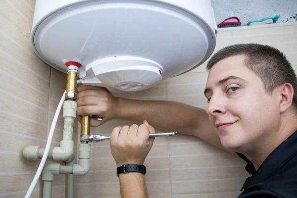 The boiler repair technician uses an adjustable wrench to unscrew or tighten the nut on the pipe. Installing a water heater or dismantling a damaged boiler for later repair.