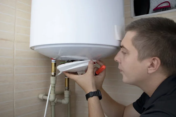 The boiler repair technician uses an adjustable wrench to unscrew or tighten the nut on the pipe. Installing a water heater or dismantling a damaged boiler for later repair.