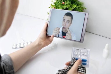 Bir kadın bir tabletle video bağlantısı ile doktorla iletişim kuruyor. Karantina koşulları altında tıbbi yardım. Uzaktan terapistle görüşme.
