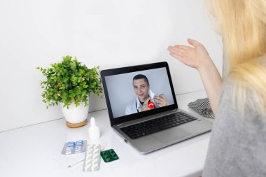 Bir kadın video bağlantısıyla doktorla bilgisayar aracılığıyla iletişim kuruyor. Karantina koşulları altında tıbbi yardım. Uzaktan terapistle görüşme.