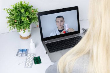 Bir kadın video bağlantısıyla doktorla bilgisayar aracılığıyla iletişim kuruyor. Karantina koşulları altında tıbbi yardım. Uzaktan terapistle görüşme.