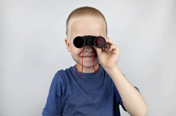 A boy with binoculars looks into the distance and smiles. Facial expression and body position show victory. The concept of vision for success, business confidence and overcoming difficulties.