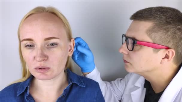 整形外科医生检查病人的耳朵 这个女孩向医生咨询如何改变耳朵的形状 — 图库视频影像