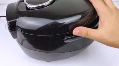 Çoklayıcının makro videosu. Adam tavayı açar ve yemeği karıştırır. Pişmiş yiyeceklerden buhar görülebilir. Mutfakta otomasyon ve kolaylık kavramı..