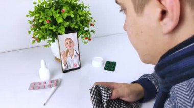 Bir adam video bağlantısıyla bir doktorla akıllı telefon aracılığıyla iletişim kuruyor. Karantina koşulları altında tıbbi yardım. Uzaktan terapistle görüşme.