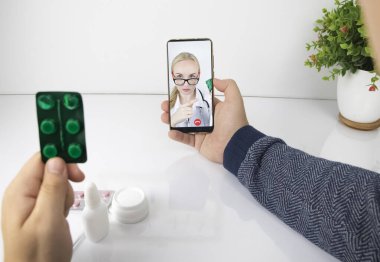 Bir adam video bağlantısıyla bir doktorla akıllı telefon aracılığıyla iletişim kuruyor. Karantina koşulları altında tıbbi yardım. Uzaktan terapistle görüşme.