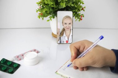 Bir adam video bağlantısıyla bir doktorla akıllı telefon aracılığıyla iletişim kuruyor. Karantina koşulları altında tıbbi yardım. Uzaktan terapistle görüşme.