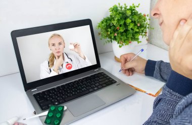 Bir adam video bağlantısıyla doktorla bilgisayar aracılığıyla iletişim kuruyor. Karantina koşulları altında tıbbi yardım. Uzaktan terapistle görüşme.