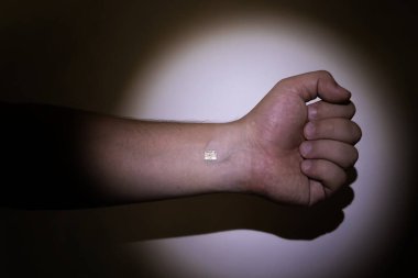 Bir polis, çipi yerleştirilmiş bir adamın eline fener tutar. Kontrol, yontma, elektronik belgeler ve kimlik doğrulama kavramı