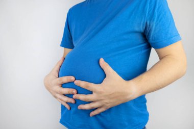Adam şişmiş karnına tutunuyor. Şişkinlik, gaz, gastrointestinal arıza. Acı içinde kıvranıyor