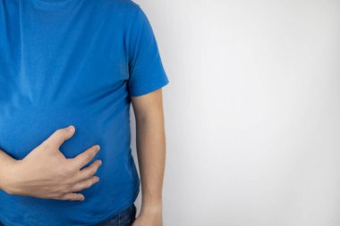 Adam şişmiş karnına tutunuyor. Şişkinlik, gaz, gastrointestinal arıza. Acı içinde kıvranıyor