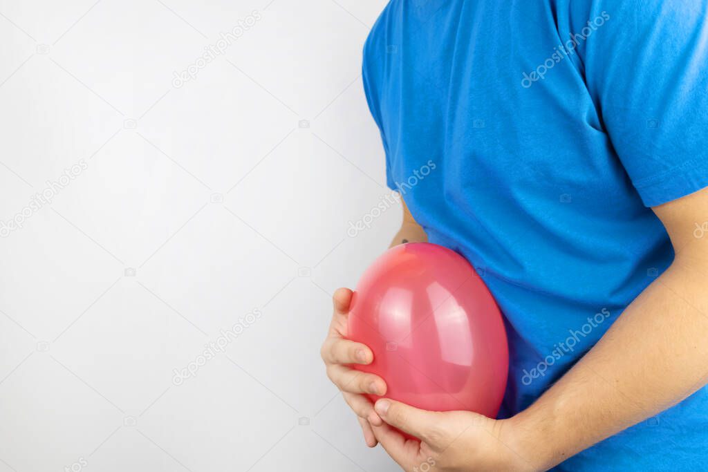 Bloating and flatulence concept. The man holds a red balloon near the abdomen, which symbolizes gas problems. Intestinal tract and digestive system