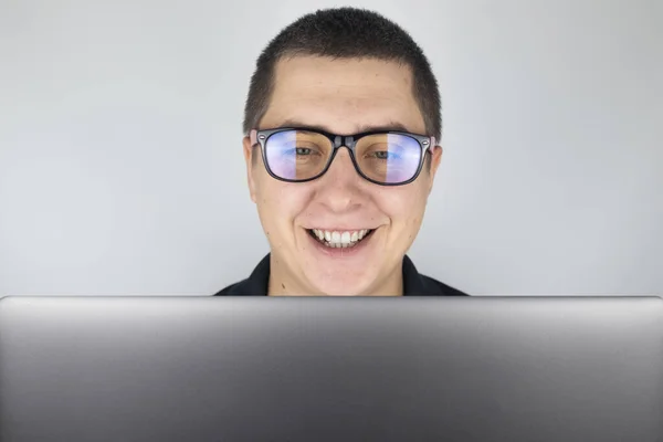 The man looks into the laptop, laughs and is surprised at what he saw there. Expression of emotions and reaction to what you see on the Internet. The concept of shocking content.