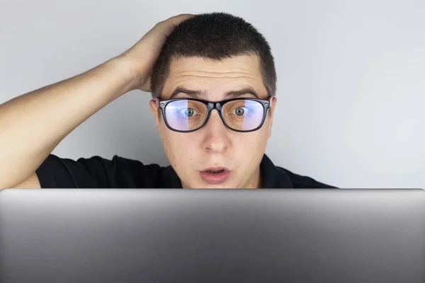 The man looks at the laptop and is frightened by what he saw there. Expressing emotions and reacting to what you see on the Internet. Shocking content concept.