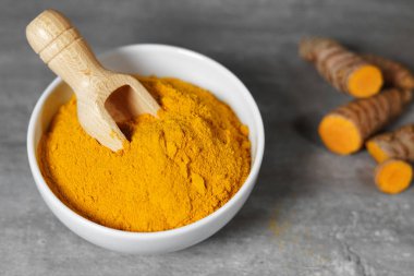 Zerdeçal tozu ve dilimlenmiş zerdeçal kök sağlıklı baharat beyaz bir kase bir ahşap Bauer ile Asya gıda closeup.