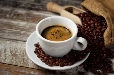 Kahve fincanı ve rustik masada kahve çekirdekleri